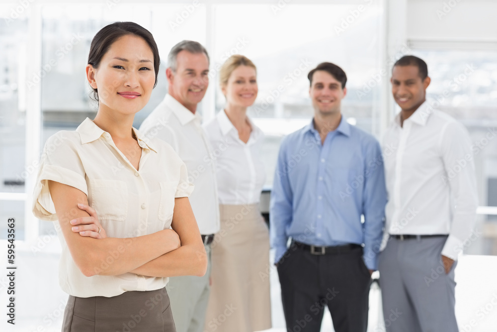 Smiling businesswoman standing with team behind her