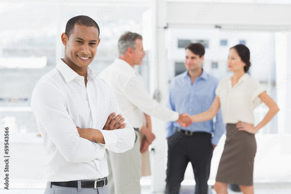 Young businessman with team behind him smiling at camera Young businessman with team behind him smiling at camera