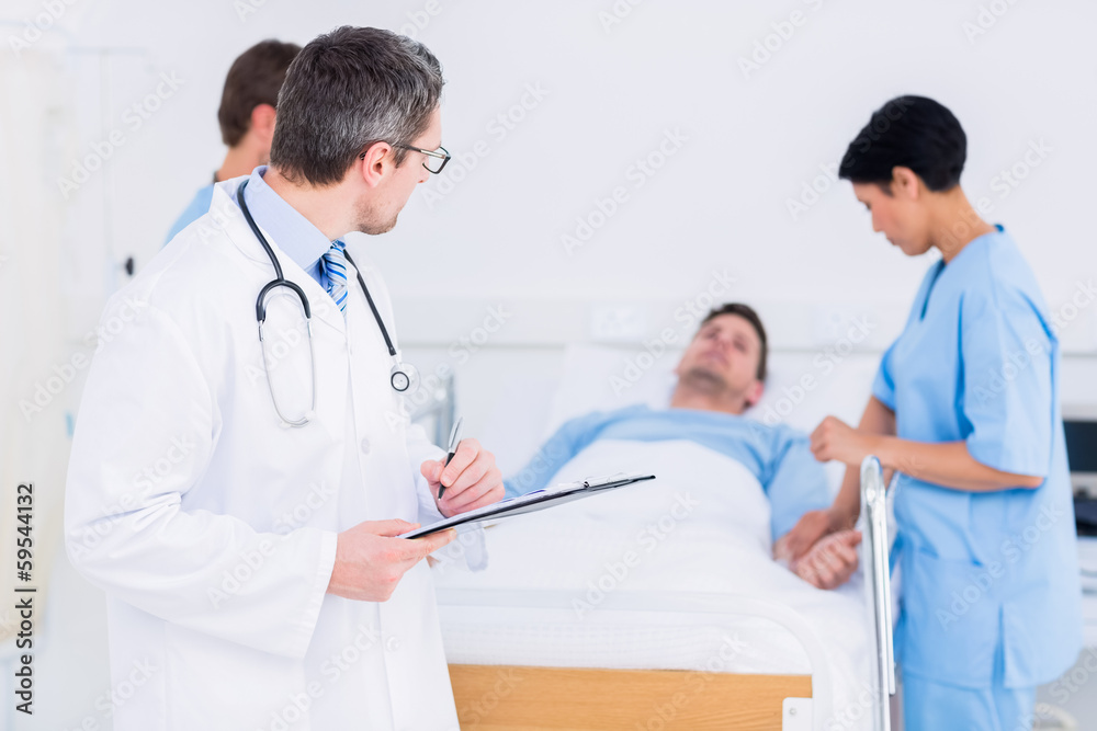 Doctor holding reports with patient and surgeon in background Doctor holding reports with patient and surgeon in background
