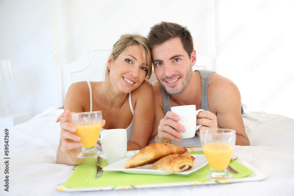 Cheerful young couple having breakfast in bed Cheerful young couple having breakfast in bed