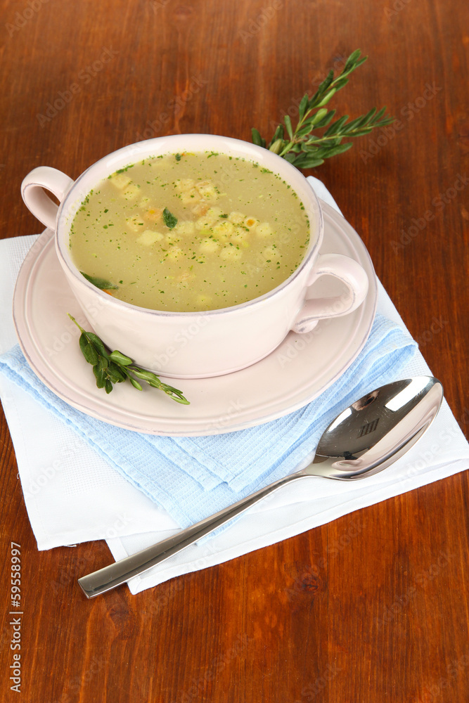 Nourishing soup in pink pan on wooden table close-up