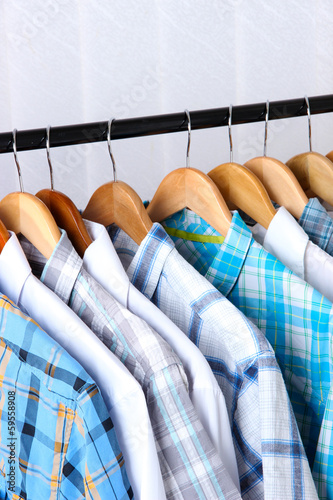 Men's shirts on hangers on light background