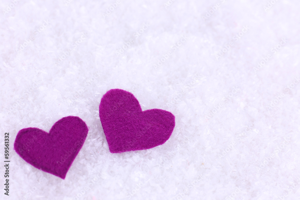 Little felt hearts on snowy background