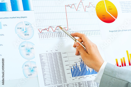 female hand pointing pen on financial charts