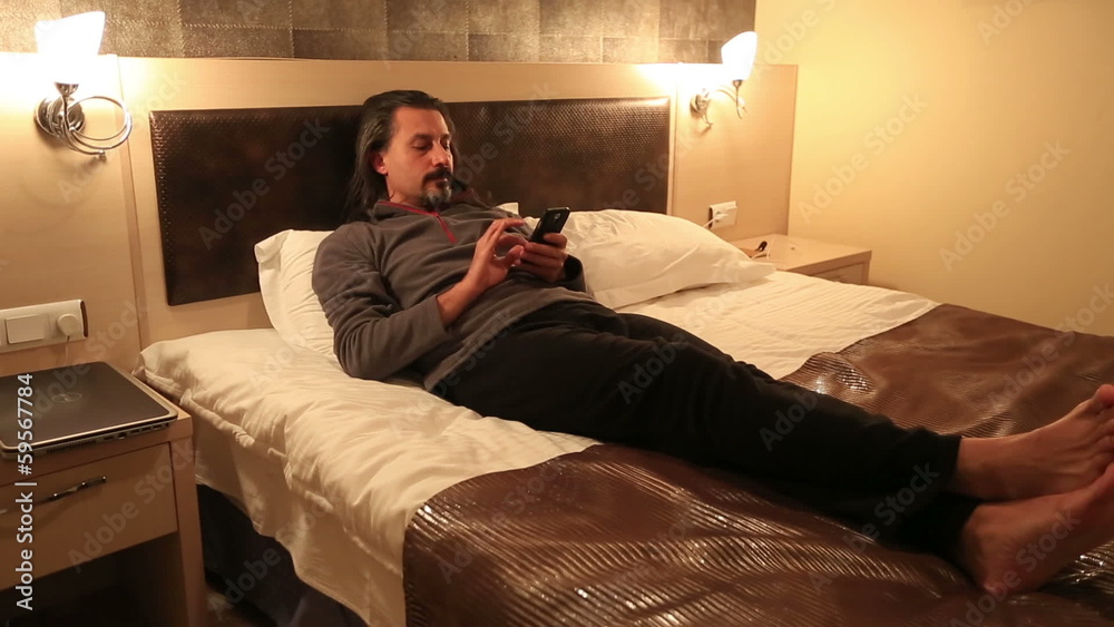attractive man using smart phone in hotel room attractive man using smart phone in hotel room