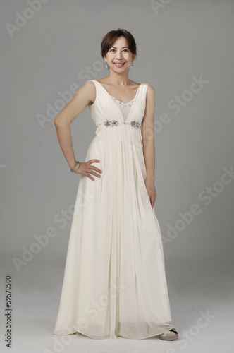 beautiful smiling girl in a white wedding dress on a gray