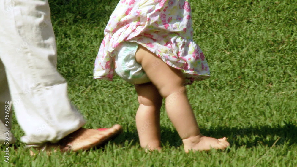 Baby girl first steps helped by mother Baby girl first steps helped by mother