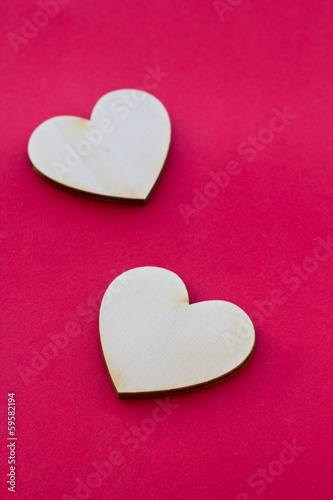 Valentine's day card with two wooden hearts symbol on red surfac