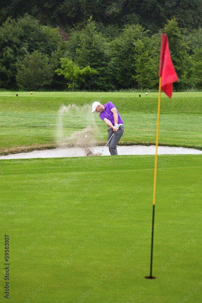 Fototapeta premium Golfer playing out of a bunker