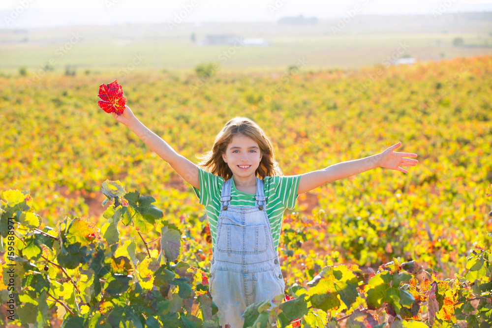 Fototapeta premium Kid girl in happy autumn vineyard field open arms with red leaf