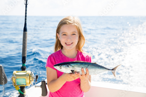 Blond kid girl fishing tuna bonito sarda fish happy catch