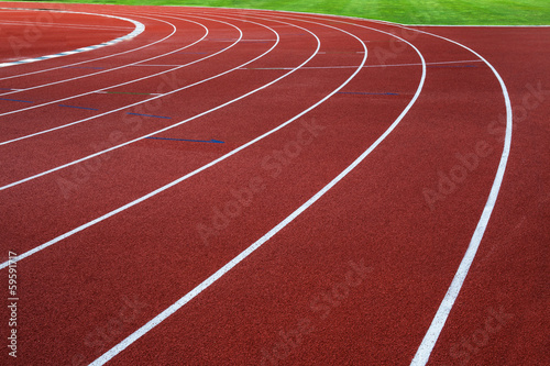 White lines on red running track with green grass.