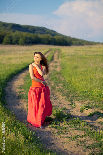 Portrait of a woman in red on a background of sky and grass