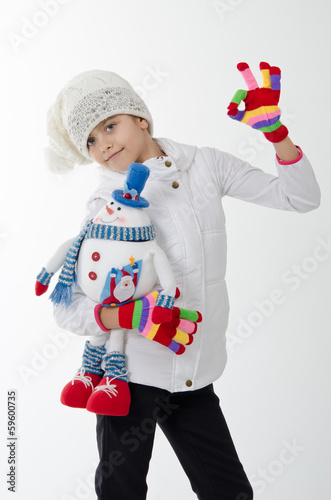 girl holding a toy snowman. Dressed in a white hat and jacket © NatBud