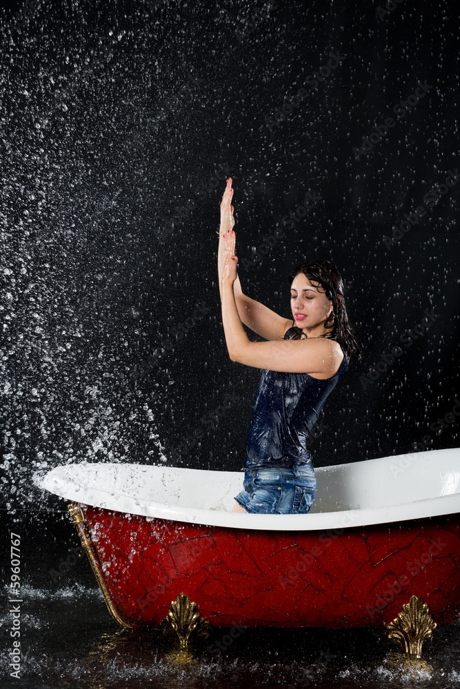 Drenched girl protected from water stands in bathtub