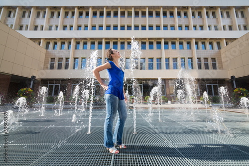 Beautiful girl having fun standing on grid with fountains photo