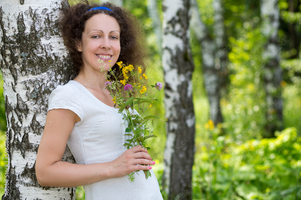 Beautiful smiling girl with flowers near the birch in nature Beautiful smiling girl with flowers near the birch in nature