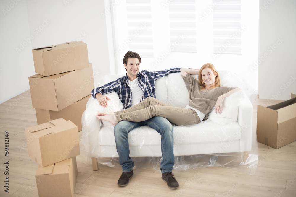 smiling couple lying on sofa in new home