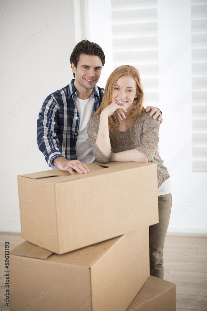 smiling couple leaning on boxes in new home smiling couple leaning on boxes in new home