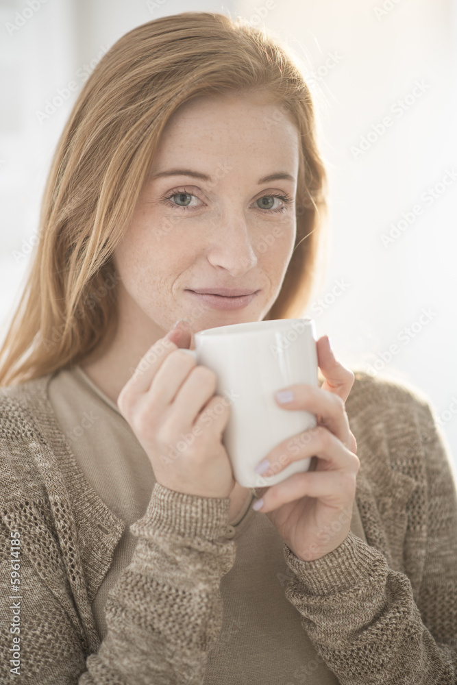 closeup of an attractive redhead young woman with a mug