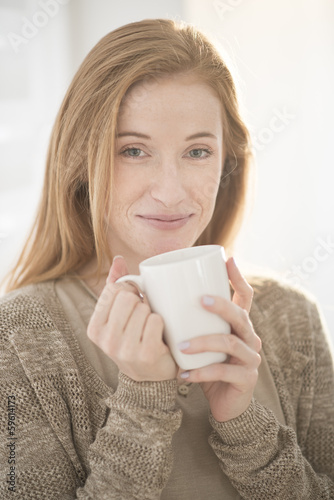 closeup of an attractive redhead young woman with a mug