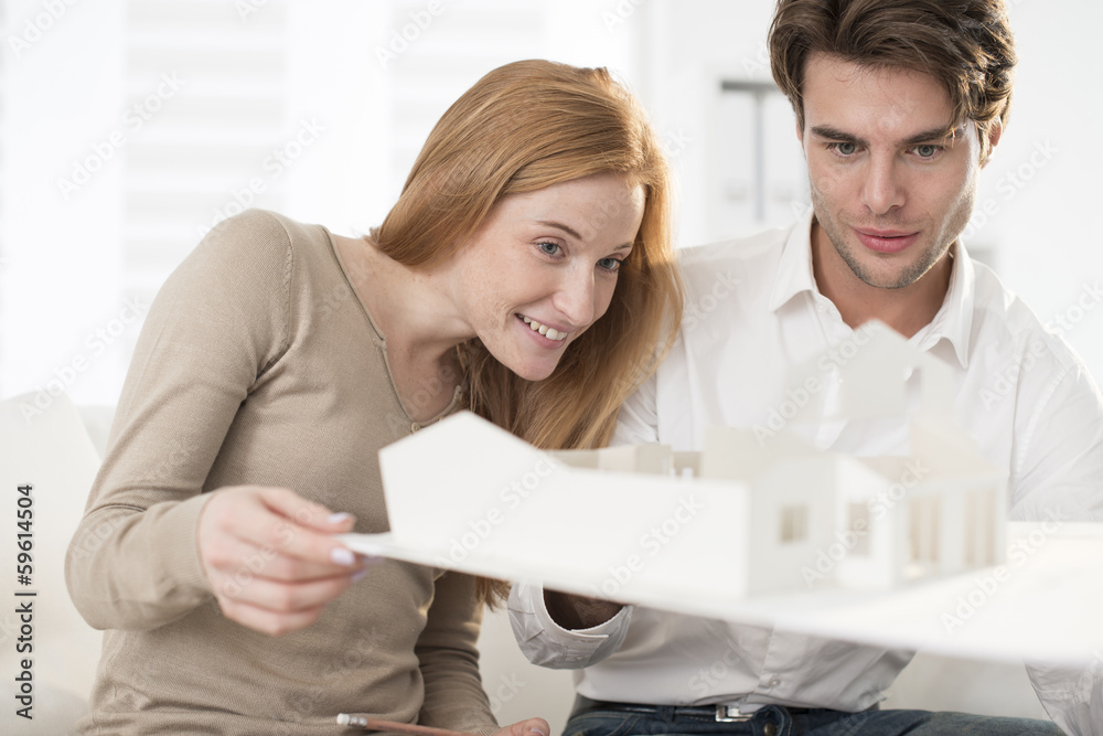 Couple studying a construction project with a model house Couple studying a construction project with a model house