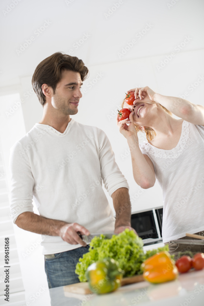 couple in the kitchen, woman makes a joke with tomatoes couple in the kitchen, woman makes a joke with tomatoes
