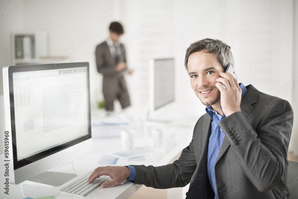 businessman at phone in office looking at camera businessman at phone in office looking at camera
