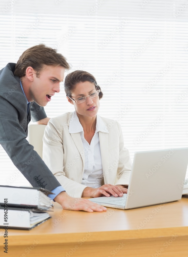 Business couple using laptop at office desk