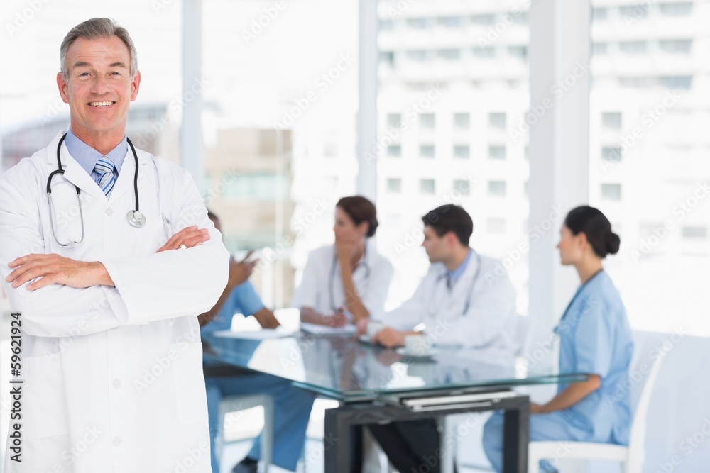 Doctor with group around table in background at hospital Doctor with group around table in background at hospital