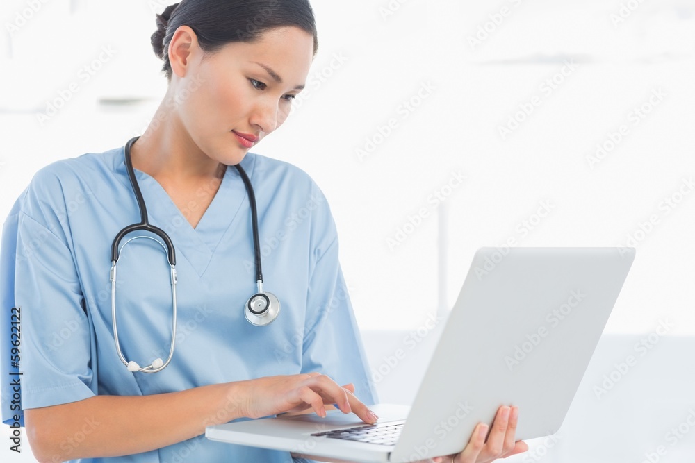 Concentrated surgeon using a laptop in hospital Concentrated surgeon using a laptop in hospital