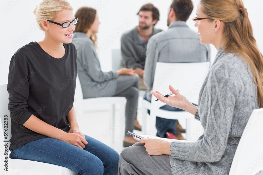 Group therapy session with therapist and client in foreground Group therapy session with therapist and client in foreground
