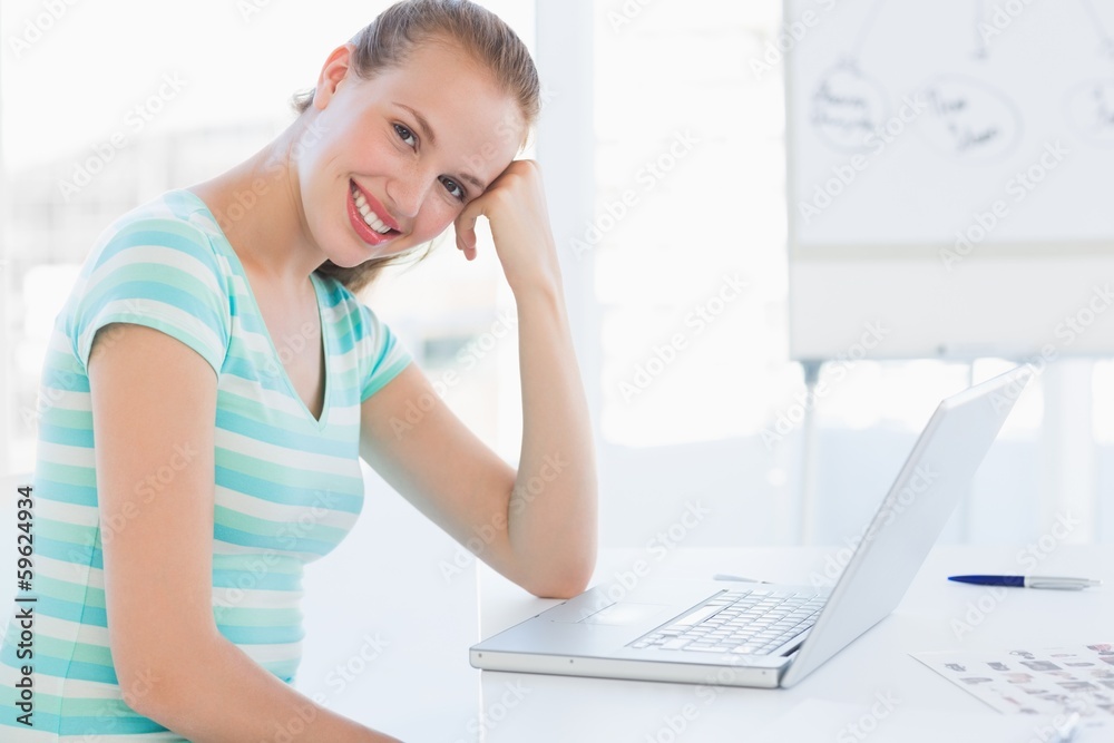 Smiling young casual woman in front of laptop at office Smiling young casual woman in front of laptop at office