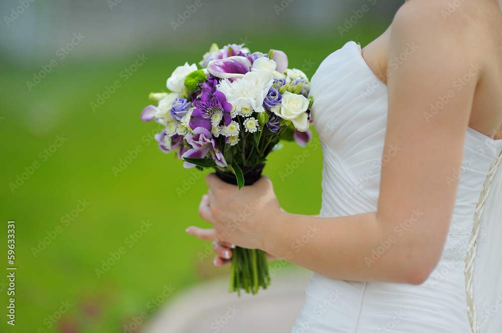 wedding bouquet in hands of the bride in profile purple flowers