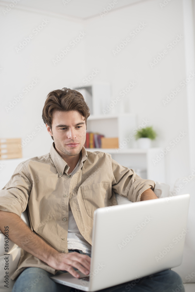 man sitting in couch using laptop computer