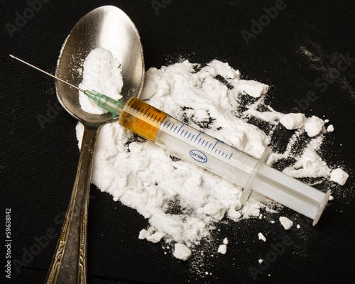 Drug syringe and cooked heroin on spoon