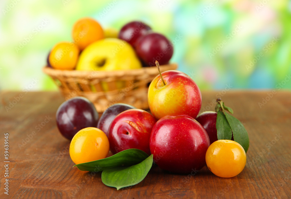 Ripe plums on wooden table on natural background