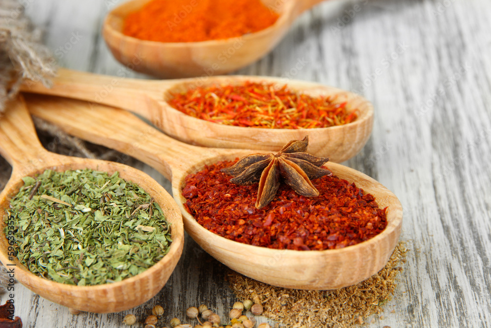 Assortment of spices in wooden spoons on wooden background Assortment of spices in wooden spoons on wooden background