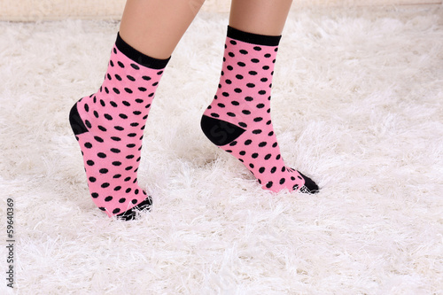 Female legs in colorful socks on white carpet background