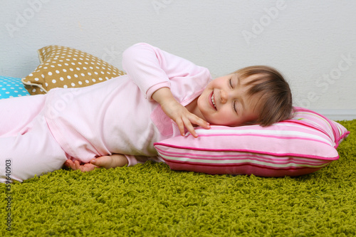Little girl lying on carpet...