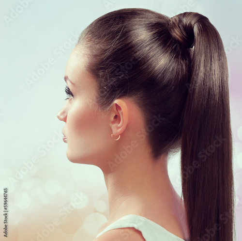 Young female with healthy shining brown hairs put in pony tail.