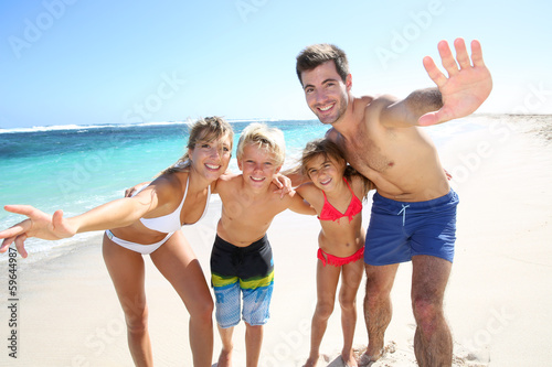 Family of four having fun at the beach © goodluz