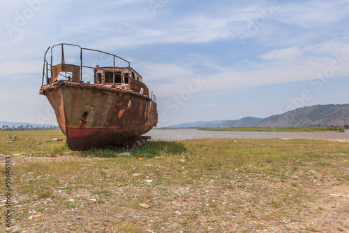 The rusty ship on river bank.