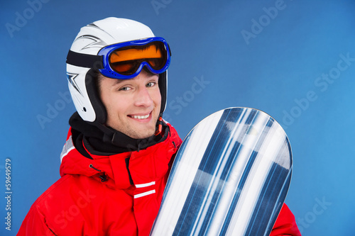 Close up of smiling male snowboarder in helmet and mask. © BlueSkyImages