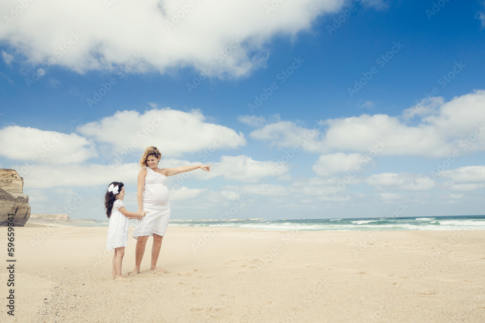 Pregnant woman and her daughter on the beach Pregnant woman and her daughter on the beach