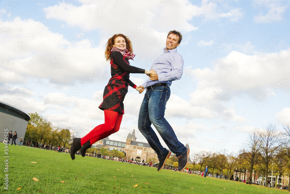Outdoor happy couple jumping in Museumplein, Amsterdam Outdoor happy couple jumping in Museumplein, Amsterdam