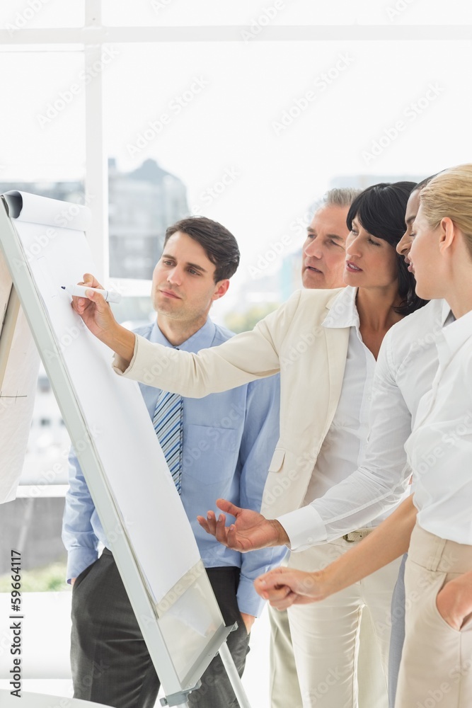 Interested colleagues watching businesswoman writing on whiteboa