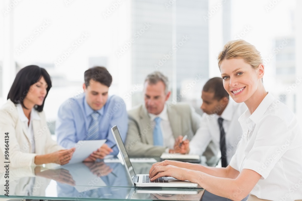 Businesswoman using her laptop during a meeting smiling at camer Businesswoman using her laptop during a meeting smiling at camer