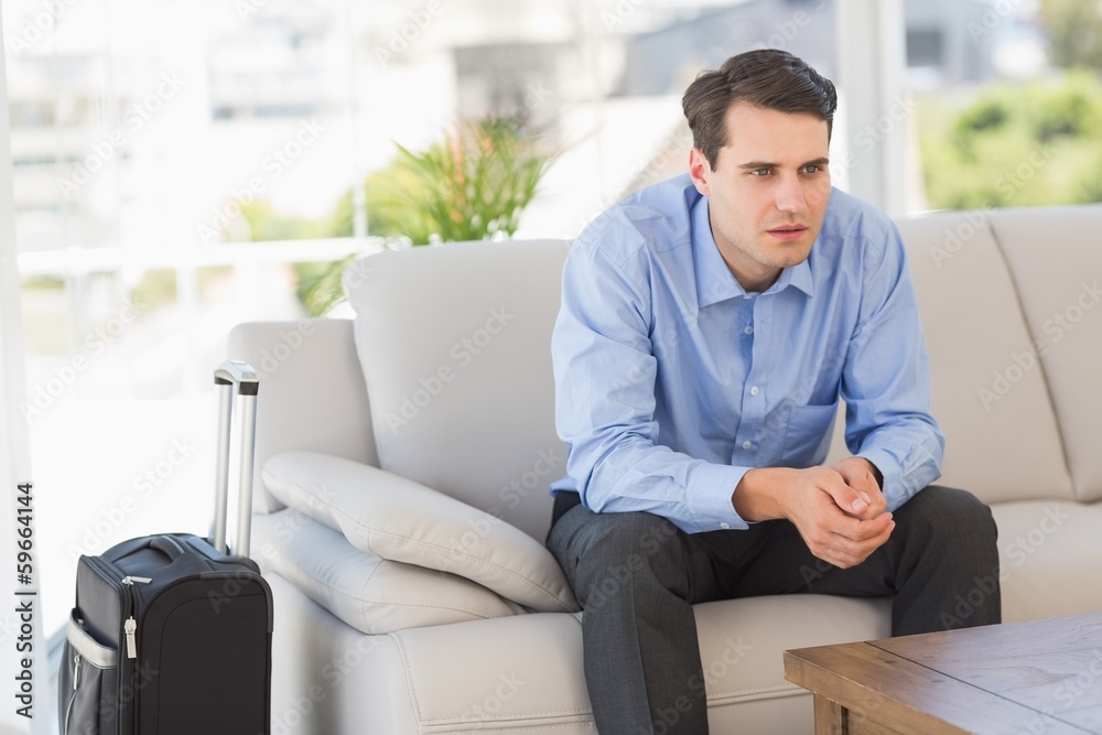 Businessman sitting on couch waiting to leave on business trip Businessman sitting on couch waiting to leave on business trip