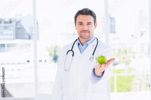 Portrait of a smiling male doctor holding an apple